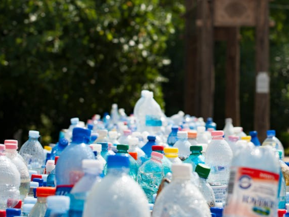 A large collection of used, clear plastic water bottles with colored caps.